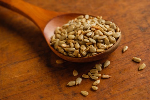 Wooden spoon full of sunflower seeds on table