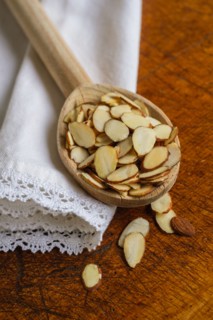 Wooden spoon full of sliced almond on table