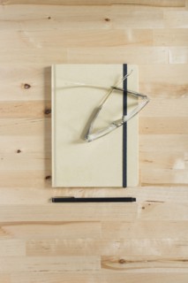 Diary, eyeglasses and pen on wooden desk