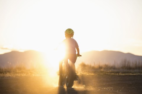 USA, Colorado, Rear view of boy (8-9) cycling at sunset