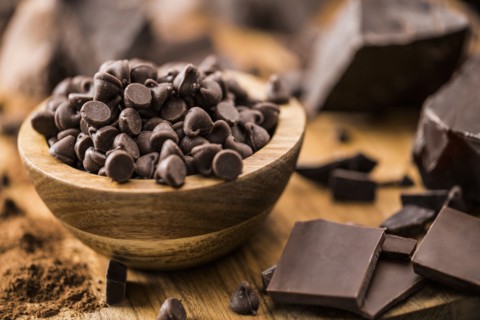 Bowl of chocolate chips and various chocolate pieces on cutting board