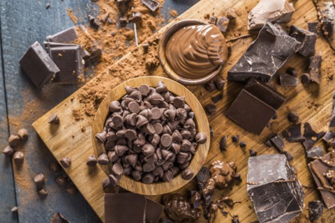 Various chocolate pieces and melted chocolate on cutting board