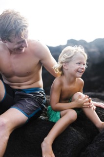 Young man with younger brother (4-5) sitting on rocks