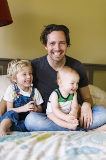 Father with sons (12-17 months, 4-5) sitting on bed