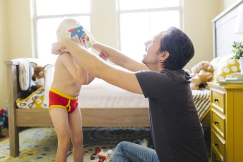 Father dressing son (4-5) in bedroom