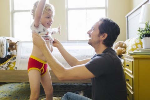 Father dressing son (4-5) in bedroom