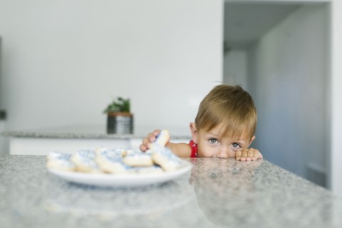 Boy (2-3) reaching for cookies on kitchen counter