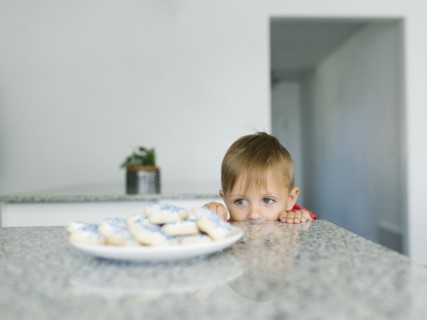 Boy (2-3) looking at cookies on kitchen counter