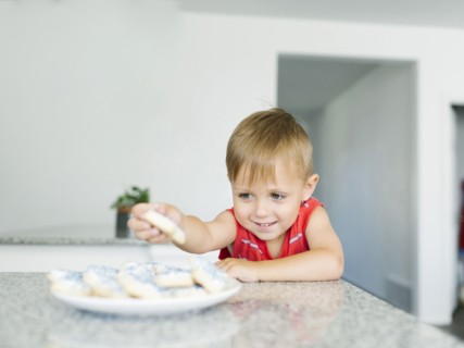 Boy (2-3) reaching for cookies on kitchen counter