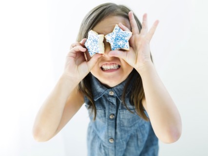 Portrait of girl (6-7) holding cookies in front of eyes