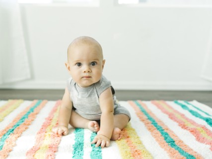 Portrait of baby boy (6-11 months) sitting on colorful carpet