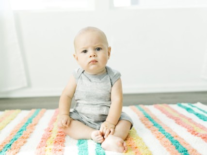 Portrait of baby boy (6-11 months) sitting on colorful carpet