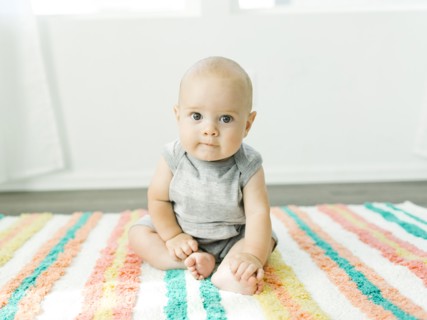 Portrait of baby boy (6-11 months) sitting on colorful carpet