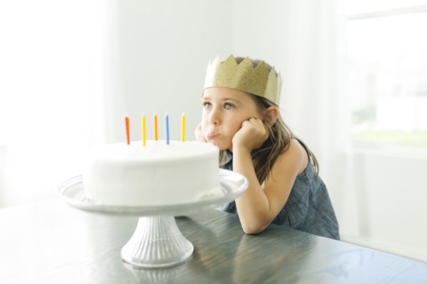 Sad girl (6-7) with birthday cake