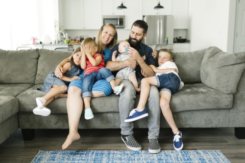 Family with four children (6-11 months, 2-3, 6-7) spending time on sofa