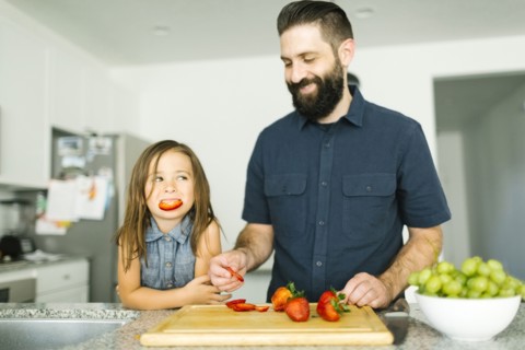 Father with daughter (6-7) eating strawberries