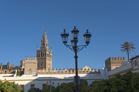 Spain, Andalusia, Seville, La Giralda bell tower of Seville cathedral with ornate street light in foreground