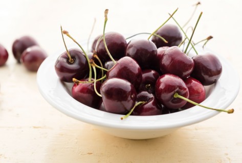 Ripe cherries in white bowl on table