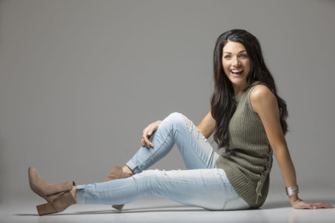 Studio shot of woman sitting on floor and laughing
