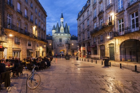 France, Nouvelle-Aquitaine, Bordeaux, Crowded sidewalk cafe with Cailhau Gate in background