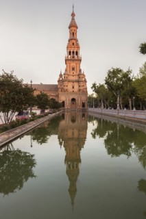 Spain, Andalusia, Seville, Plaza de Espana, Tower reflecting in water surface