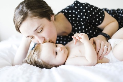 Baby girl (6-11 Months) being kissed by mother