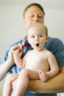 Father and baby girl (12-17 months) brushing hair after bath
