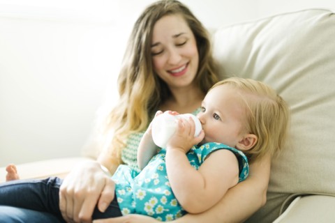 Mother feeding baby girl (12-17 months) in living room