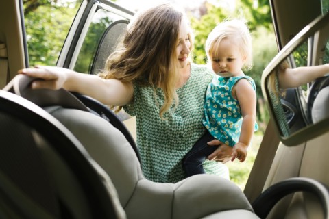 Mother preparing baby girl (12-17 months) for car trip