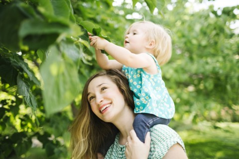Mother carrying daughter (12-17 months) on shoulders