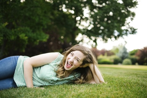 Portrait of woman lying on grass and laughing