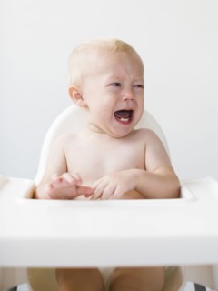 Baby boy (12-17 months) sitting in high chair and crying