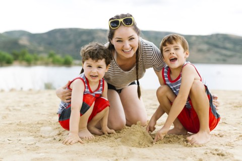 Mother playing with sons (4-5, 6-7) on beach by lake