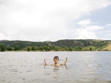 USA, Utah, Park City, Boy (6-7) flexing muscles in lake