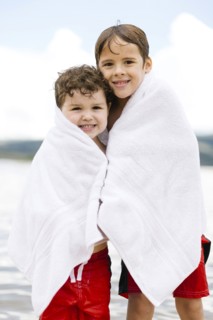 Portrait of brothers (4-5, 6-7) wrapped in towels standing by lake