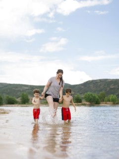 Mother with sons (4-5, 6-7) wading in lake