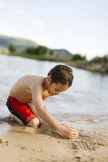 Boy (6-7) playing on beach by lake