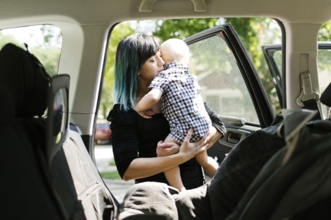 Mother carrying baby boy ( 12-17 months ) into car
