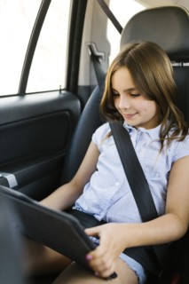 Girl ( 8-9) sitting in car and using digital tablet