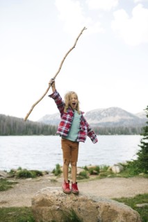 USA, Utah, Midway, Boy with stick (6-7) standing on rock by lake