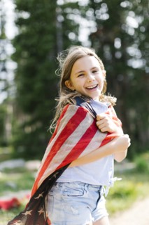 Portrait of girl (8-9) wrapped in us flag in forest