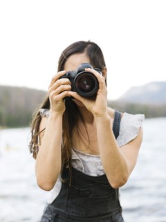 Woman taking pictures by lake