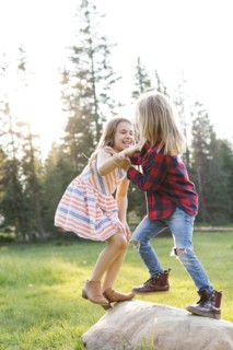 Boy (6-7) and girl (8-9) play-fighting in forest