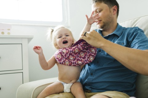 Father dressing daughter (12-17 months)