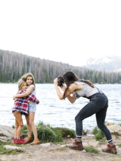 Mother photographing girl (8-9) and boy (6-7) by lake