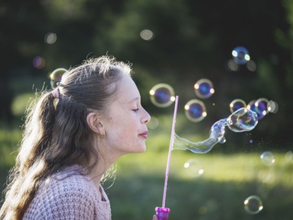 Girl (12-13) blowing bubbles