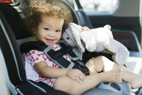 Girl (12-17) sitting on car seat and holding plush toy