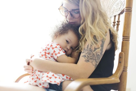 Mother sitting on chair and rocking daughter (12-17 months)