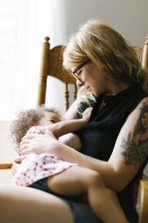 Mother sitting on chair and breastfeeding daughter (12-17 months)