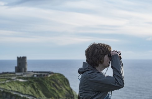 Ireland, Clare County, Woman looking through binoculars on Cliffs of Moher
